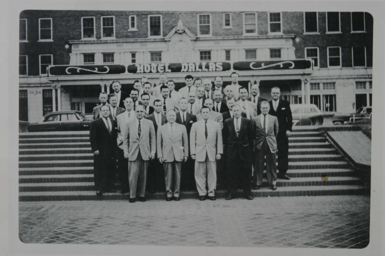 Group of people standing on steps in front of a building. 