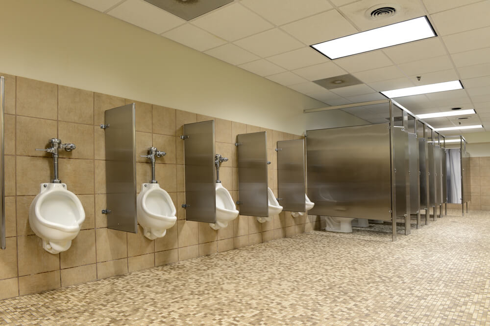 Row of urinals and toilet cubicles in a public restroom.